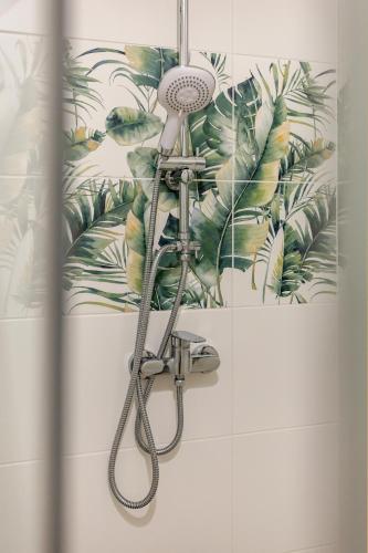a shower in a bathroom with a tropical wallpaper at Apartament Flora - apartament blisko morza in Gdańsk