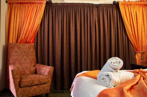 a bedroom with a bed and a chair and curtains at Zoete Rust Boutique Hotel in Lephalale