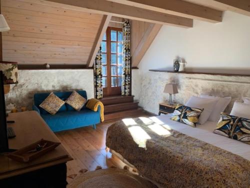 a bedroom with a large bed and a blue couch at Maison d'hôtes La Bageatière - Lac d'Aiguebelette in Lepin-le-Lac