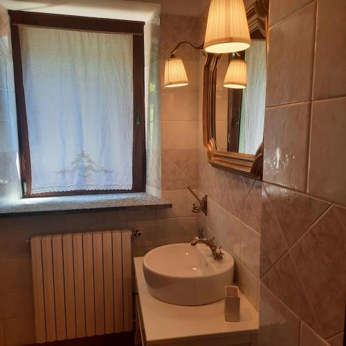 a bathroom with a sink and a mirror and a window at CascinaMirta in Andorno Micca