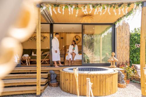 a couple standing on the deck of a house with a hot tub at Bruval Eco Retreat in Sandim