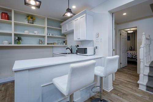 a kitchen with white cabinets and a counter with two chairs at The Elizabeth Manor Guesthouse in St. John's