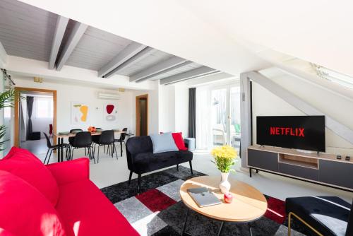 Luxury 4-rooms apartment with terrace في براغ: غرفة معيشة مع أريكة حمراء وتلفزيون