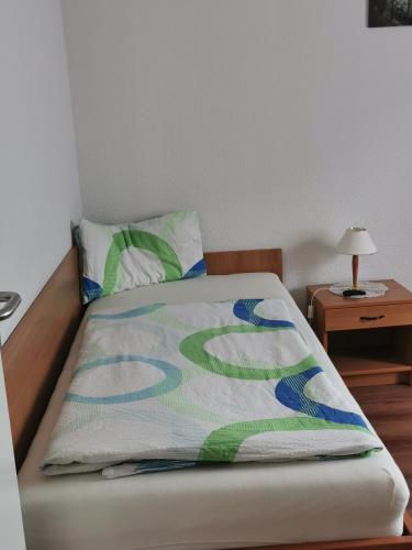 a bed with a colorful blanket on top of it at Pension zum Park in Goldberg