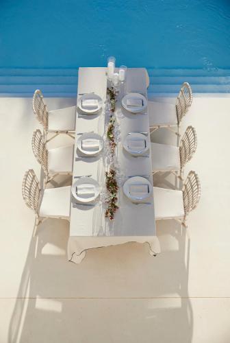 a white table with white chairs and a table with flowers at Octant Vila Monte in Moncarapacho