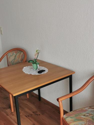 a wooden table with a vase of flowers on it at Pension zum Park in Goldberg