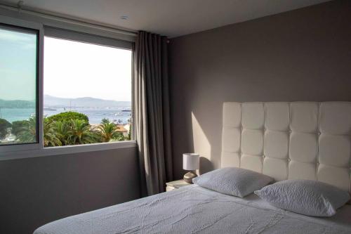 a bedroom with a white bed with a large window at Sérénité Marines ‣Incredible Sea view in Saint-Tropez