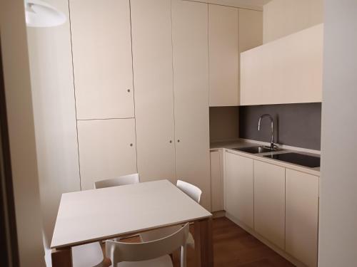Una cocina con gabinetes blancos y una mesa y sillas. en Chill in Tuscany ground floor, en Lucca