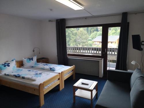 ブランケンハイムにあるHotel Finkenbergのベッド2台、ソファ、窓が備わる客室です。
