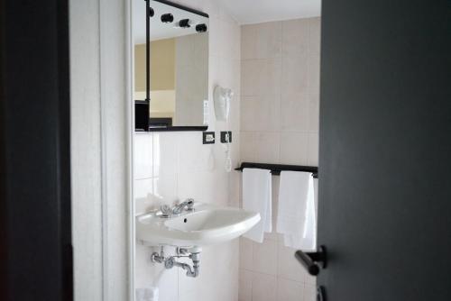 Baño blanco con lavabo y espejo en Hotel Italia, en Porretta Terme