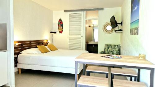 een slaapkamer met een bed en een tafel. bij L’Aurora – Agréable studio équipé à la Marina du Gosier in Le Gosier