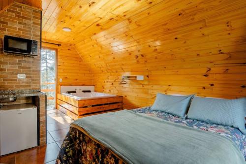 a bedroom with a bed in a wooden cabin at Chale com hidromassagem Casa Papai Noel in Campos do Jordão