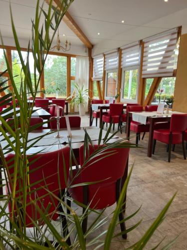 a restaurant with red chairs and tables and windows at Gasthaus Am Colphus in Barby