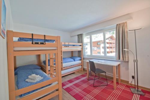 Kleines Zimmer mit Etagenbetten und einem Schreibtisch. in der Unterkunft Haus Matten, Apartment Breithorn in Zermatt