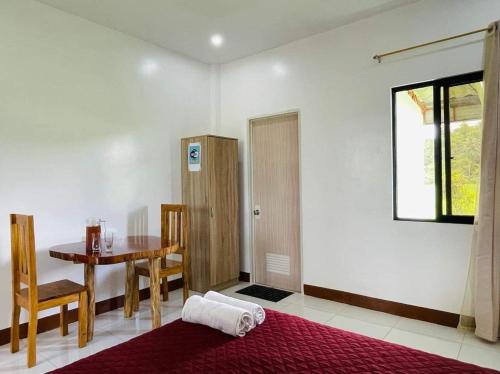 a room with a table and a bed and a window at Jazz Ferme Inn Batuan Bohol in Batuan