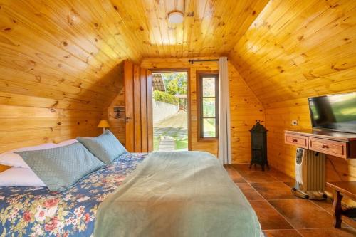 a bedroom with a bed and a television in a cabin at Chale com hidromassagem Casa Papai Noel in Campos do Jordão