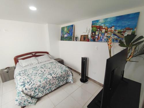 a bedroom with a bed and a painting on the wall at Beautiful and bright studio apartment with rooftop in Cali
