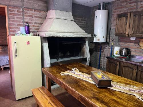 cocina con fogones y mesa de madera con nevera. en Renacer en Malargüe