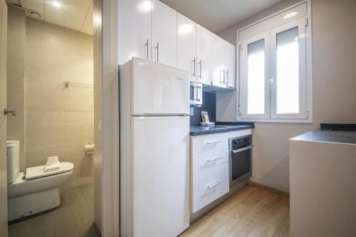 a white kitchen with a refrigerator and a toilet at Catalunya Casas 2 bed apartment in Barceloneta steps from the beach in Barcelona