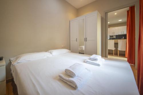 Un dormitorio con una cama blanca con toallas. en Catalunya Casas 2 bed apartment in Barceloneta steps from the beach, en Barcelona