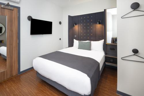a bedroom with a large bed and a tv at Point A Hotel London Kings Cross – St Pancras in London