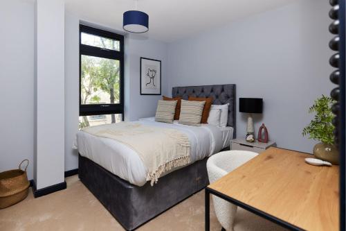 a bedroom with a large bed and a table at The Whitechapel Place - Stunning 2BDR Flat with Balcony in London