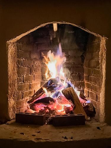 a brick fireplace with a fire in it at Unicorn Reborn - Peaceful Rentals in San Marcos La Laguna
