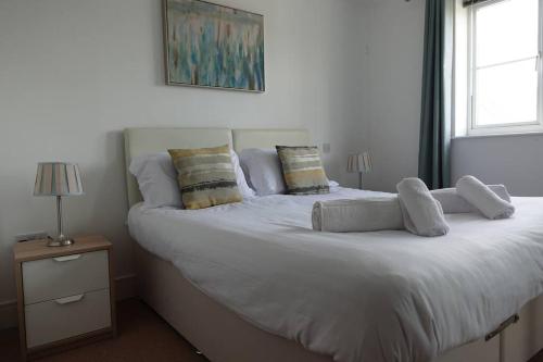 a large white bed with pillows on top of it at Guest Homes - Axial Apartment in Colchester