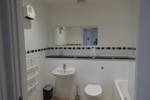 a white bathroom with a sink and a toilet at Guest Homes - Axial Apartment in Colchester