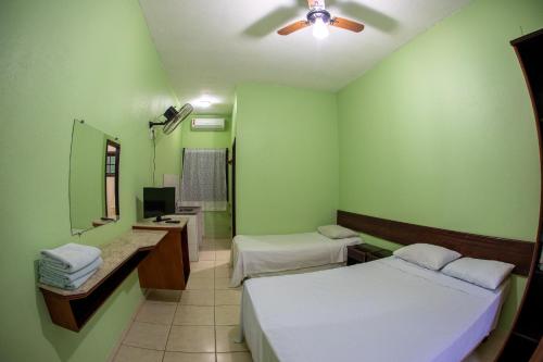 um quarto com 2 camas, um lavatório e um espelho em Pousada Praia Enseada - Marvile no Guarujá