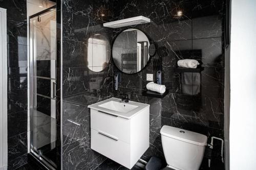 a black tiled bathroom with a toilet and a sink at AU COEUR DES MONTAGNES in Pierrefitte-Nestalas