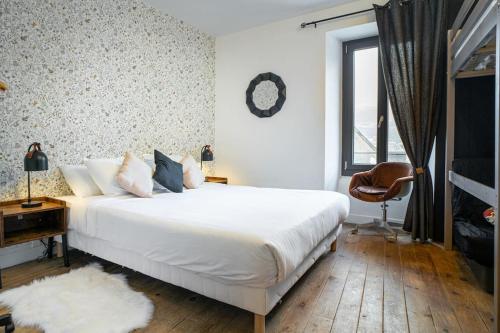 a bedroom with a large white bed and a chair at AU COEUR DES MONTAGNES in Pierrefitte-Nestalas