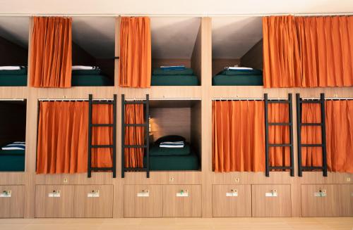 Zimmer mit orangefarbenen Vorhängen und Etagenbetten in der Unterkunft The Penida Project in Nusa Penida