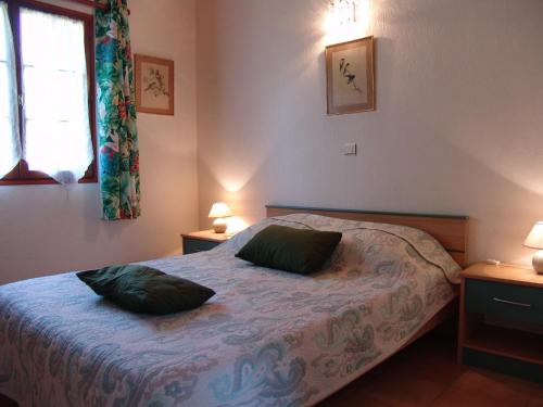 une chambre avec un lit avec deux oreillers verts dessus dans l'établissement Les Petits Prés, à Vitrac