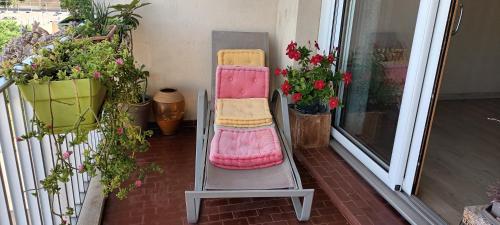 uma cadeira rosa sentada numa varanda com plantas em Appartement confortable centre ville em LʼIsle-sur-la-Sorgue