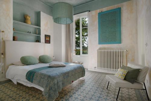 a bedroom with a bed and a chair and a window at B&B Maison Felisa in Sabran