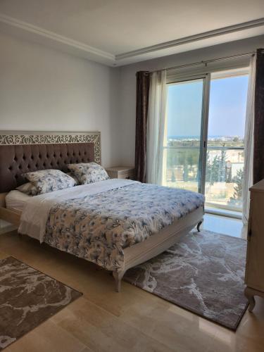 1 dormitorio con cama y ventana grande en Kantaoui appartement haut de gamme, en Hammam Sousse