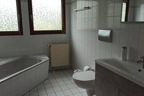 a bathroom with a tub and a toilet and a sink at Wohnung mit Spielplatz, Kaninchen und Whirlpool in Grafenhausen