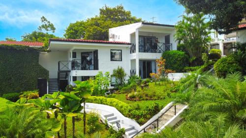 una casa con un jardín delante de ella en Villa Roca Boutique Resort & Suites - ADULT ONLY, en Manuel Antonio