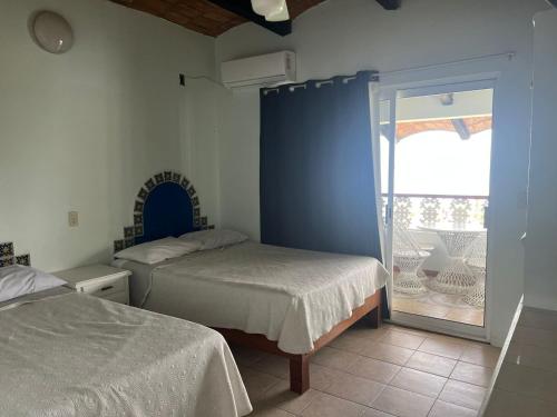 a bedroom with two beds and a sliding glass door at HOTEL VILLAS EL DORADO in Rincon de Guayabitos