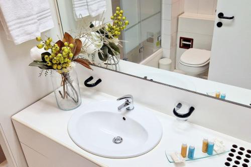um lavatório de casa de banho com um vaso de flores e um espelho em Milano 3 Suite em Basiglio