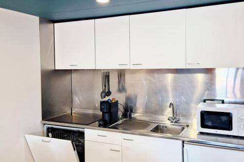a kitchen with white cabinets and a sink and a microwave at Milano 3 Suite in Basiglio