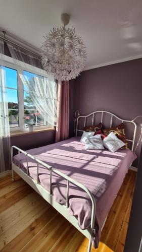 ein Schlafzimmer mit einem Bett mit lila Bettwäsche und einem Kronleuchter in der Unterkunft Jūrmalas māja in Salacgrīva
