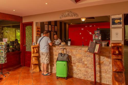 Un uomo in piedi in un bar con una valigia verde di Leyenda Boutique Hotel & Spa a Sámara