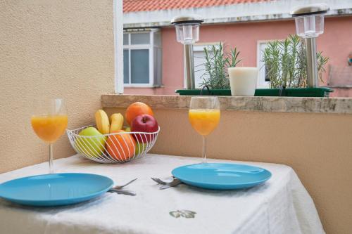 a table with two glasses of orange juice and a bowl of fruit at Bright and quiet apartment in Amadora