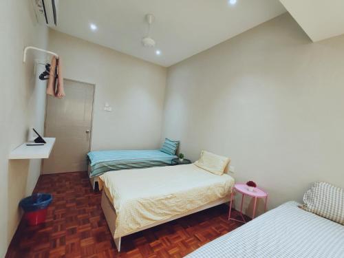 a small room with two beds and a table at A Humble Abode Homestay By irainbow in Ipoh