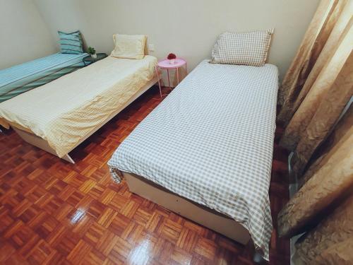 two twin beds in a room with a wooden floor at A Humble Abode Homestay By irainbow in Ipoh