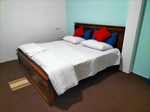 a bedroom with a bed with red and blue pillows at Kithaya Ella in Ella