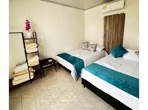Habitación con 2 camas y estante con toallas en Apartamento Familiar Buga - Basílica señor de los milagros en Buga