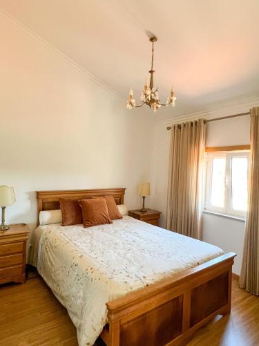 a bedroom with a large bed and a chandelier at Quinta das Covas - Trancoso in Trancoso